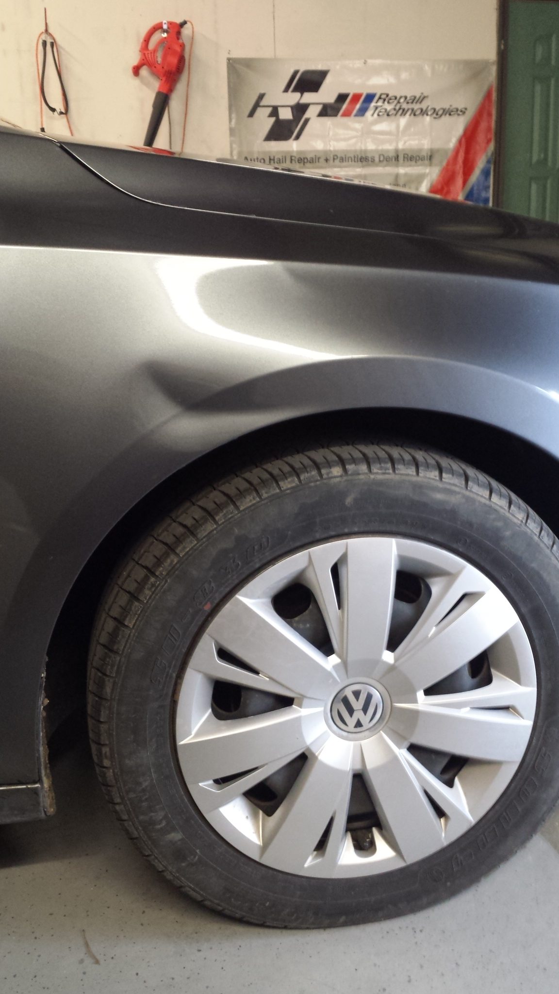 A dent in the rear quarter panel of a silver Volkswagen before repair